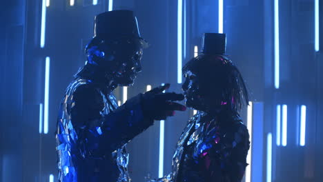 Two-dancers-a-man-and-a-woman-standing-opposite-each-other-in-time-to-the-music-dance-in-glittering-mirrored-costumes-in-blue-violet-the-color-of-shimmering-neon.